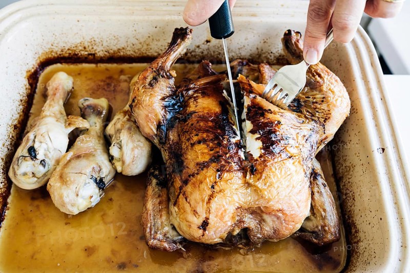 Woman carving homemade whole roasted chicken on plate