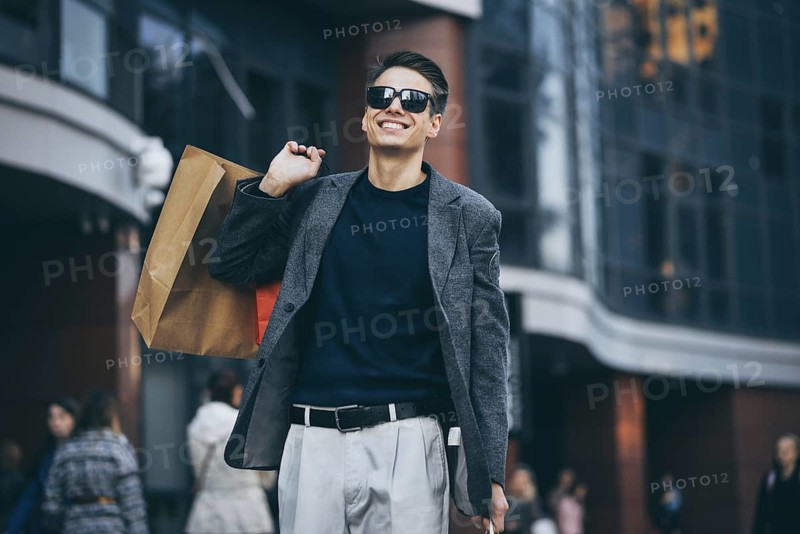 Serious cool guy with sunglasses and paper bags walking at street