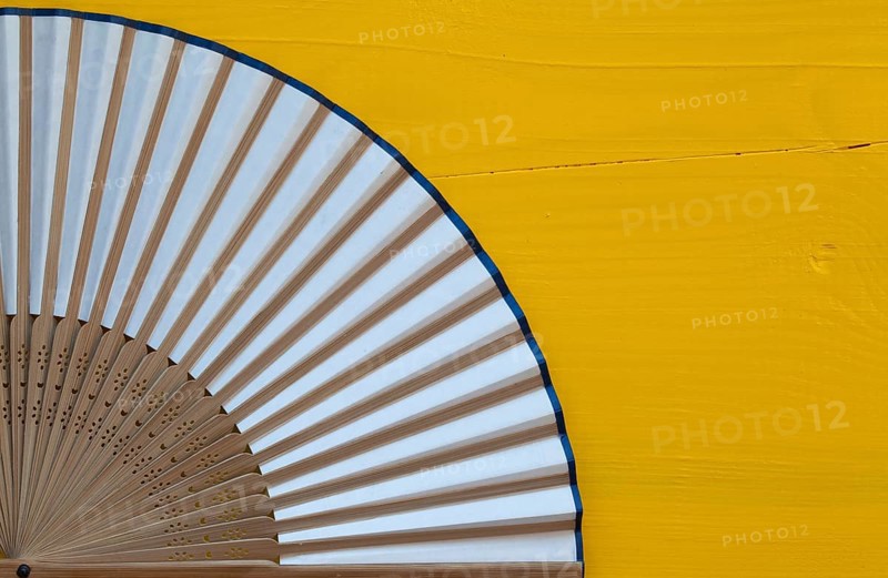 Typical Japanese hand fan made on the wooden yellow table
