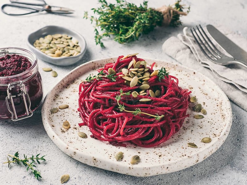 Beetroot pesto or hummus. Homemade beet pesto sauce in glass jar and fresh thyme on dark black background. Copy space for text. Ideas and recipes for healthy vegetarian detox diet food
