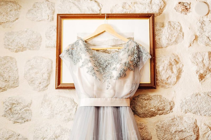 White wedding dress of the bride with patterns on a hanger on the picture frame.