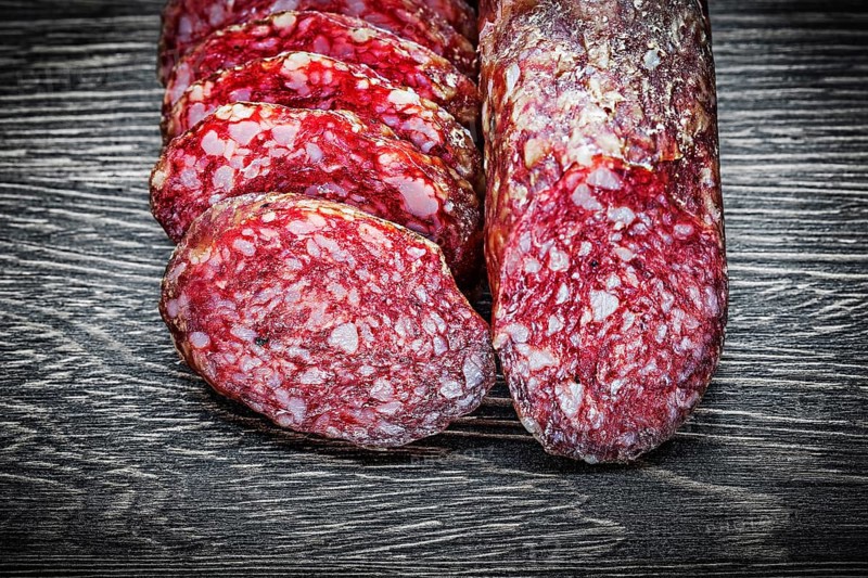 Sliced salami on wooden board top view food concept