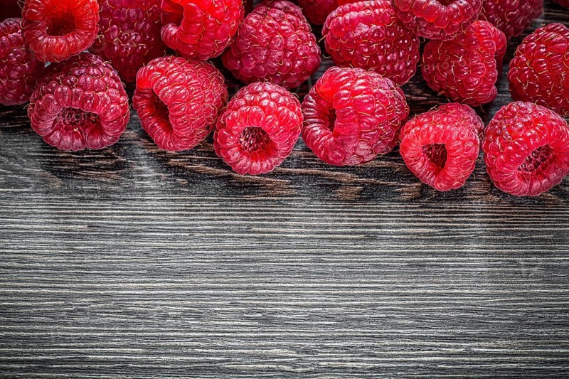 Raspberries on wooden background top view