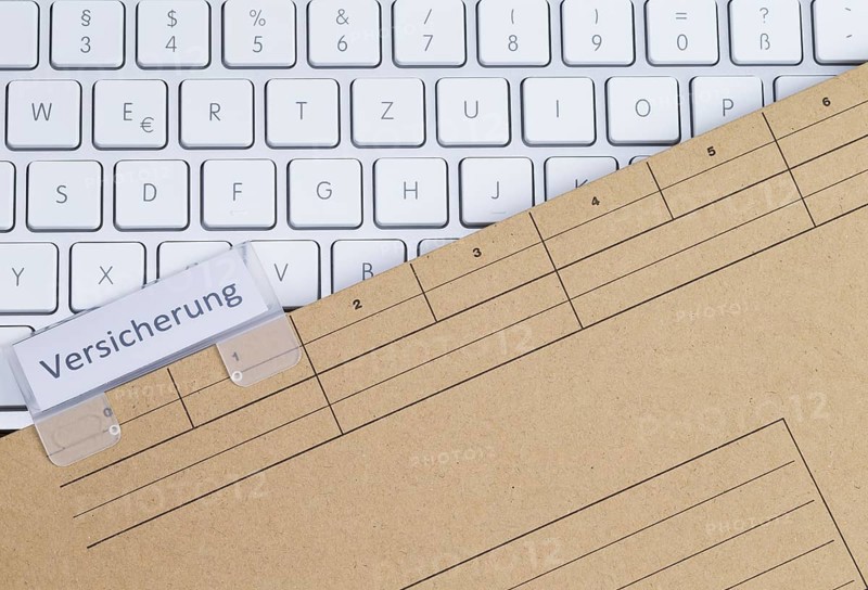 The photo shows a white keyboard with an insurance file folder