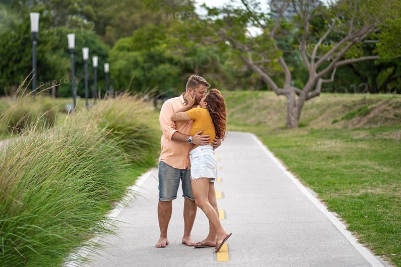 Couple stops for a moment to kiss during their walk through a park