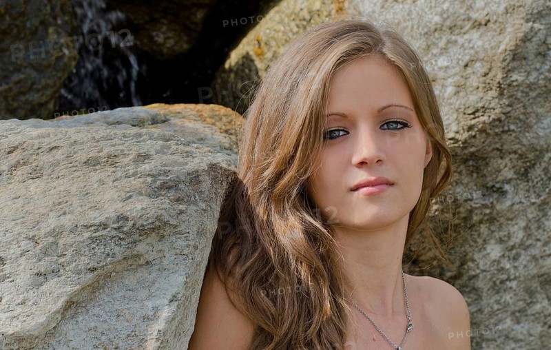 Headshot of pretty blue eyed, brunette girl against rocks