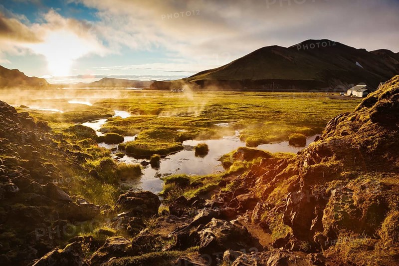 Above the source of thermal water steam rises. White nights in Iceland. Sunrise Park Landmannalaugar