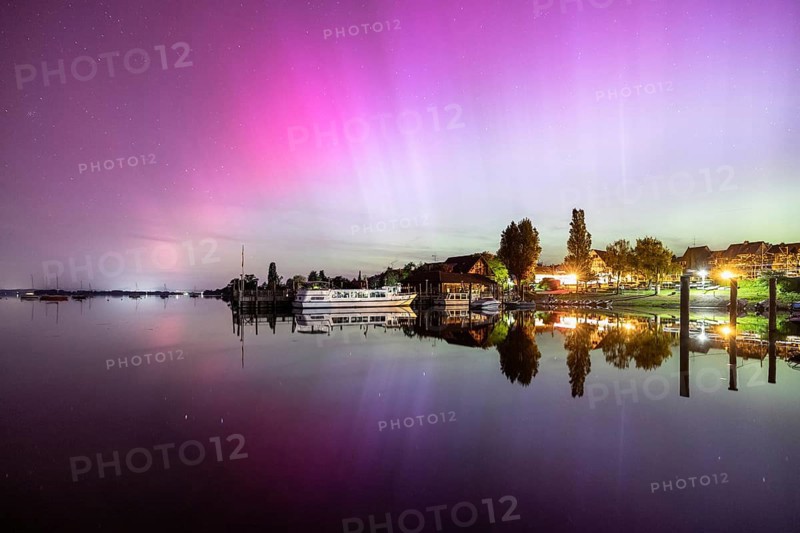 A calm lake at night, surrounded by shining auroras and reflecting houses, harbour, Allensbach, Lake Constance, Baden-Württemberg, Germany, Europe