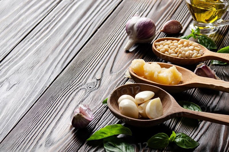 Closeup view at wooden spoons with food ingredients for genovese pesto sauce on kitchen table