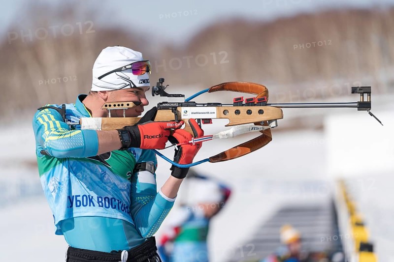 Sportsman biathlete aiming rifle shooting in standing position. Kazakhstan biathlete Kireyev Vladislav in shooting range Junior biathlon competitions East of Cup. Kamchatka, Russia, April 14, 2019, Europe