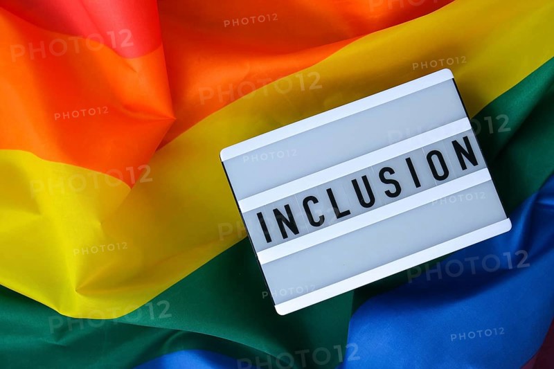 Rainbow flag with lightbox and text INCLUSION. Rainbow lgbtq flag made from silk material. Symbol of LGBTQ pride month. Equal rights. Peace and freedom. Support LGBTQ community