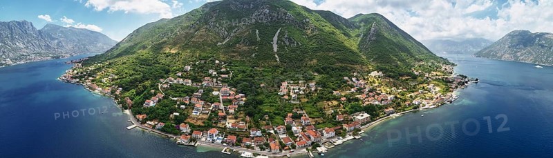Old houses with red roofs on the seashore on the slope of a green mountain. Montenegro. Drone. Panorama., Kotor Municipality, Montenegro, Europe