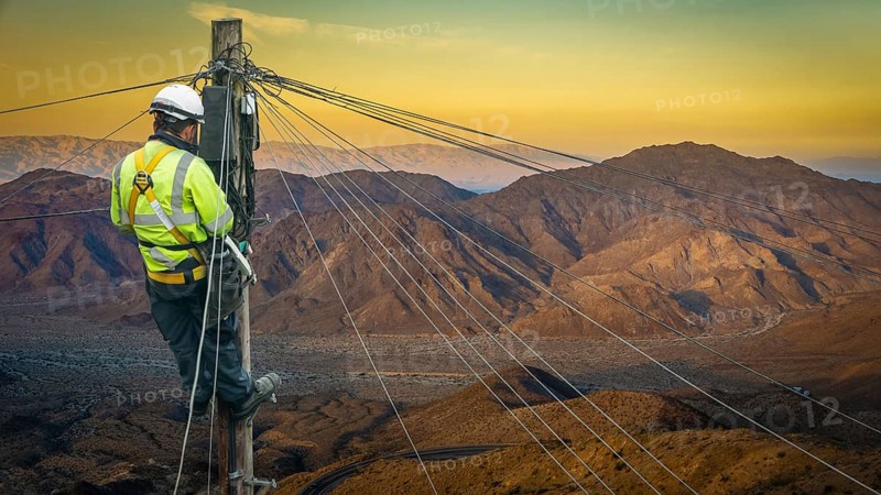 Lineman (Or Lineworker or Engineer) In A Remote Desert Landscape Fixing A Telephone Line