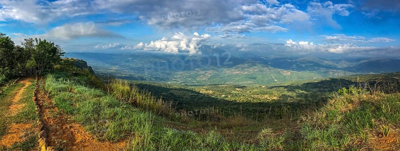 Panorama over the cliffs into a green valley and mountains in sun and shadow, blue sky and white clouds Barichara, Colombia, South America