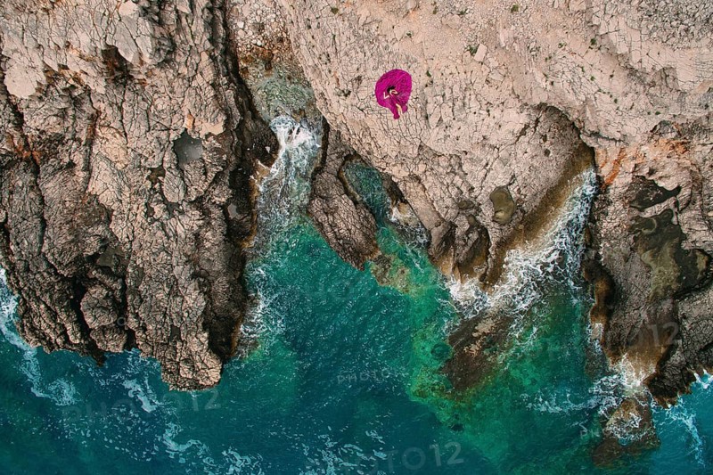 A girl in a purple dress rests on a rocky beach in Montenegro, aerial photography, Herceg Novi, Montenegro, Europe