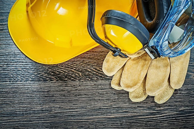 Protective gloves glasses earmuffs building helmet on wooden board