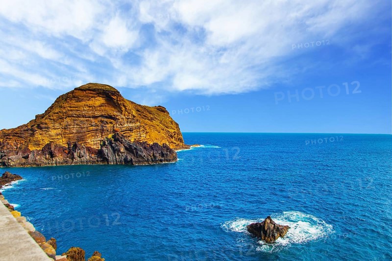 Calm bay with azure water. Rocks and stones off the shores of the volcanic island of Madeira. The concept of ecological and exotic tourism