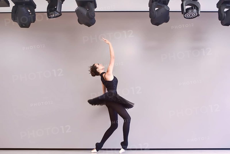 Young ballet dancer black swan practicing before performance in black tutu, classical dance studio, copy space