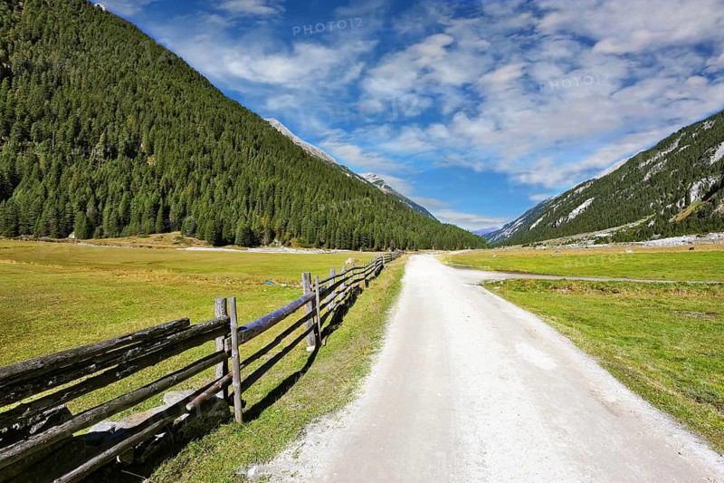 Headwaters National Park Krimml waterfalls. Rural idyll. Farm fields separated from the dirt road a low fence made ??of logs
