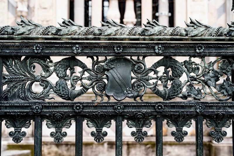 Antique wrought iron fence near the Duomo Cathedral in Milan with spikelets, shields, flowers and curls.