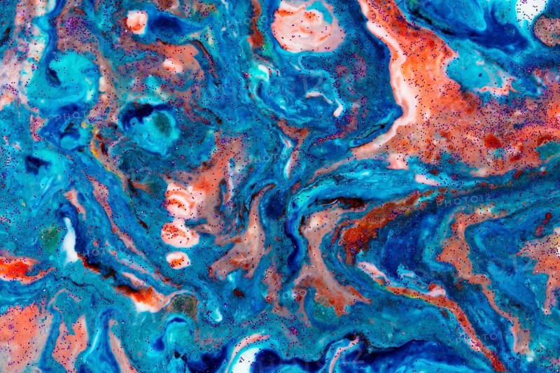 The background is acrylic blue with red lines and sparkles. Colourful marble texture. Liquid, fluid marble. Art picture. Avant-garde creativity
