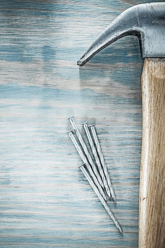 Vertical image of claw hammer nails on wooden board construction concept