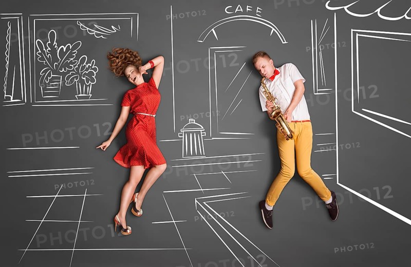 Love story concept of a romantic couple against chalk drawings background. Male playing the saxophone on the street for his girlfriend