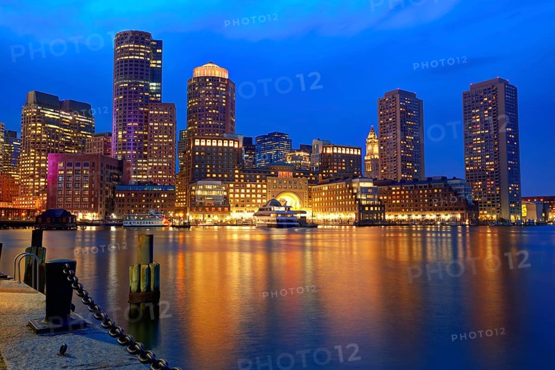 Boston\'s skyline glows at sunset, reflecting off the water at Fan Pier.