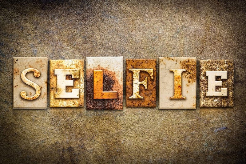 The word SELFIE written in rusty metal letterpress type on an old aged leather background