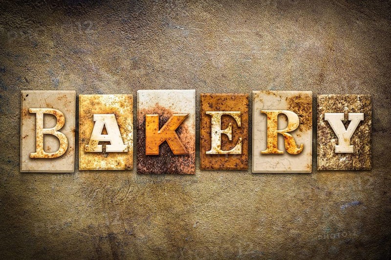 The word BAKERY written in rusty metal letterpress type on an old aged leather background