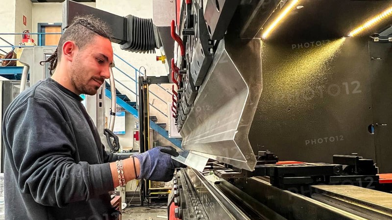 Young worker bending metals on a press brake. Metalworking industry