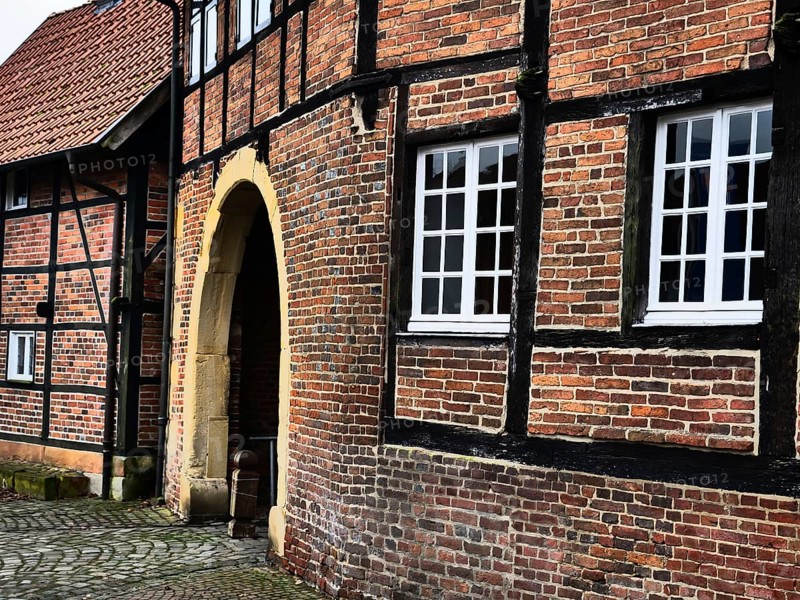 A close-up of a half-timbered house with brick walls and white windows, next to an archway, asbeck, legden, Münsterland, North Rhine-Westphalia, Germany, Europe