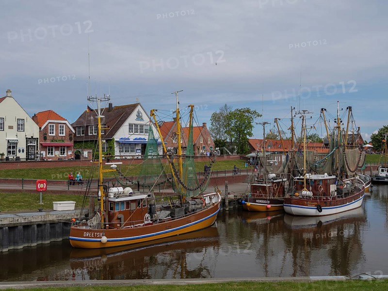 Fishing boats are anchored in the harbour, in the background houses and a maritime atmosphere, Greetsiel, East Frisia, Lower Saxony, Germany, Europe