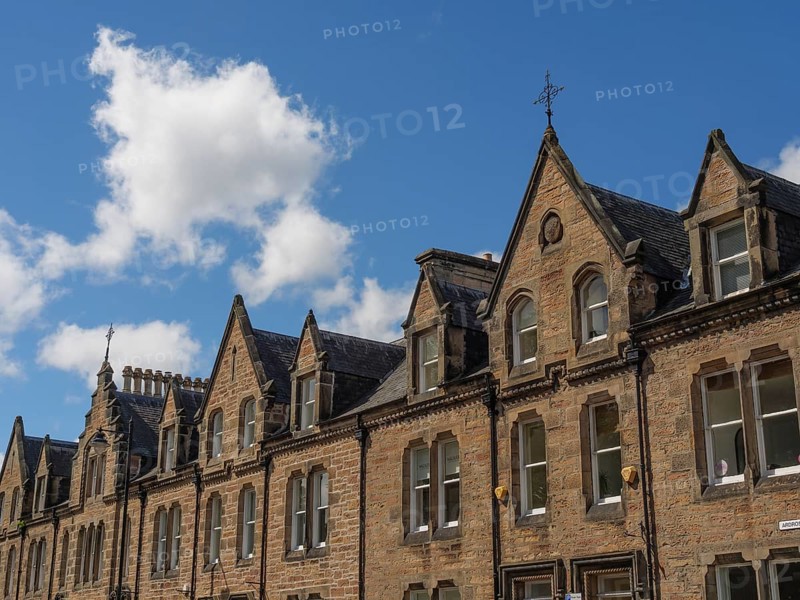 Row of historic buildings with pointed gables and stone facades under a blue sky in a cityscape, inverness, scotland, Great Britain