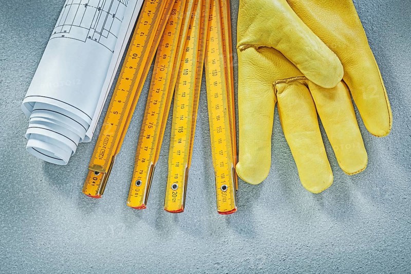 Set of safety gloves construction drawings wooden meter on concrete background building concept