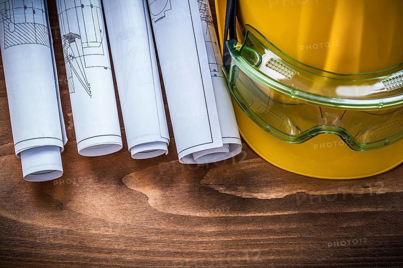 Goggles construction plans and hard hat on brown wood board