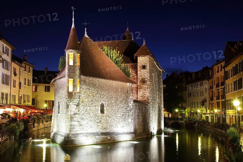 The capital of the Haute-Savoie - Annecy. The main attraction of the city - an ancient fortress-prison on an island in the middle of the river. Fortress beautifully lit and reflected in the dark water