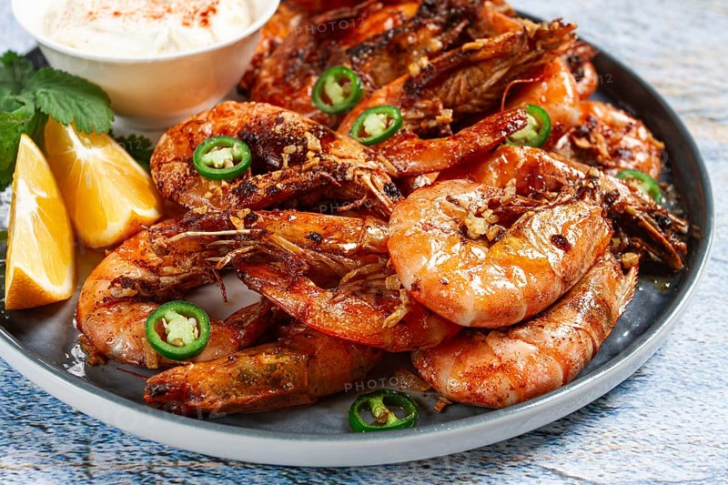 Grilled shrimps served with hot sauce and slices of fresh lemon, homemade, no people