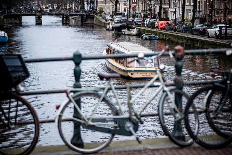 A canal tour boat navigates the web of canals in the central region of the city of Amsterdam, The Netherlands, Europe
