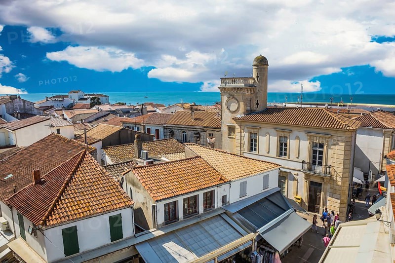 Orange and yellow tiled roofs of Provencal city Saintes-Maries-de-la-Mer. Mediterranean Sea. The concept of ethnographic tourism