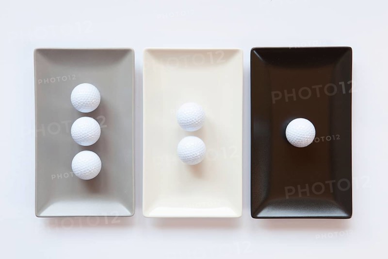 Different ceramic dishes with golf balls on over white background, rectangle dish