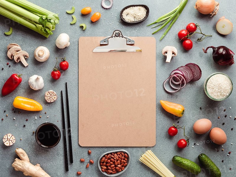 Asian ingredients and empty clipboard. Various of Chinese cooking ingredients and chopsticks on gray stone background. Asian food recipes concept. Copy space for text. Top view or flat lay