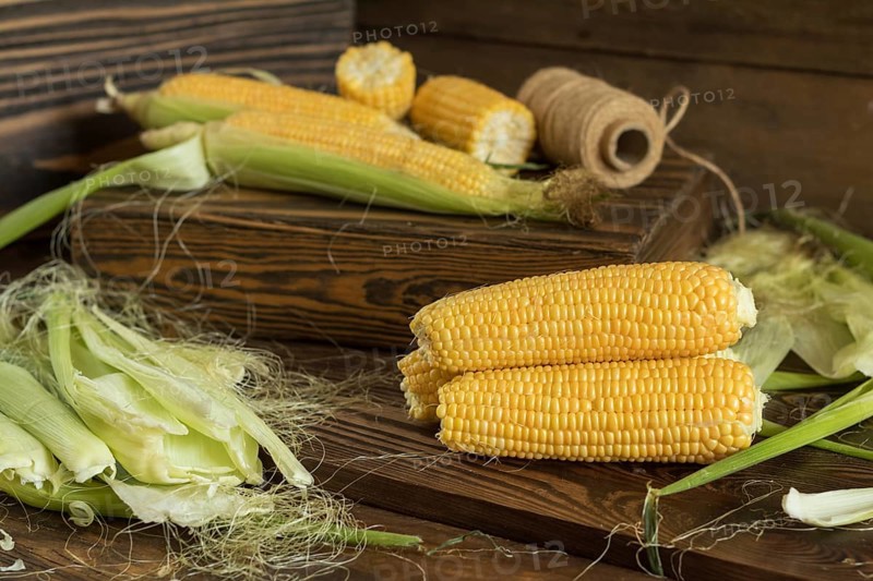 Fresh sweet corn on cobs on rustic wooden table, close up. Toned. Shallow depth of field