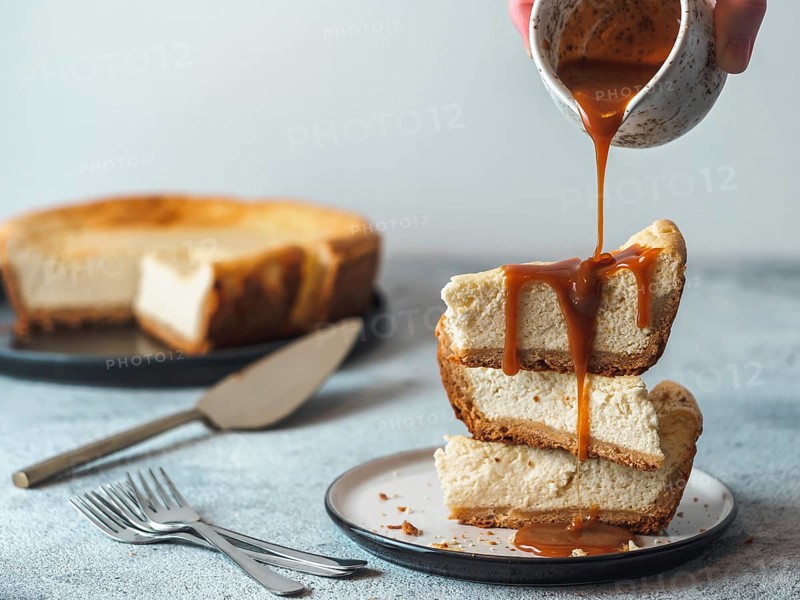 Caramel pouring on stack of three cheesekace pieces. Cheesecake with caramel on gray cement background. Copy space for text