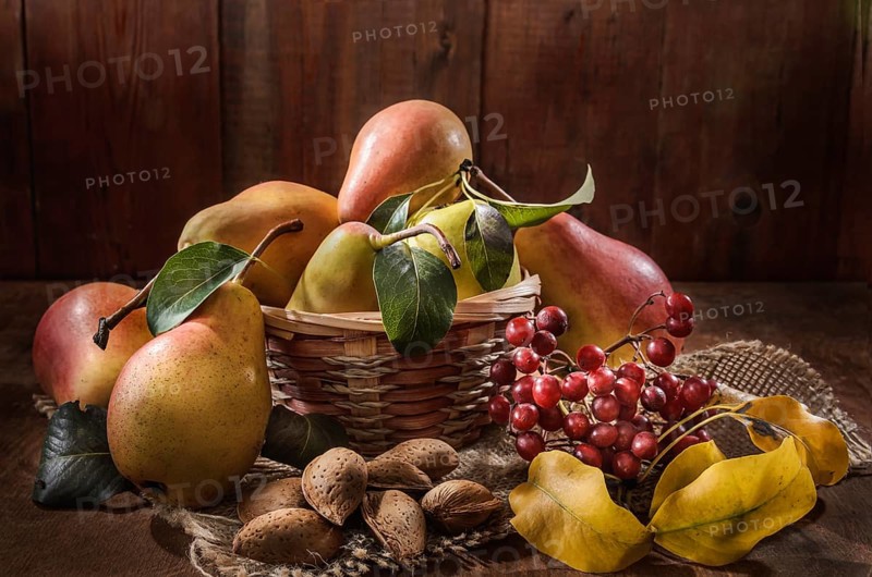 Ripe pear and a bunch of viburnum berries on a dark wooden background in a rustic style