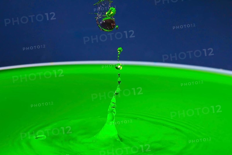 Green liquid splashes in a dynamic moment against a blue background, water droplets, collision, high-speed photography, concept, figures