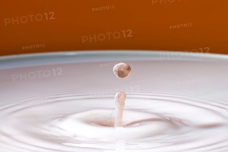 A gentle drop falls into milk and develops soft, concentric circles, water droplets, collision, high-speed photography, concept