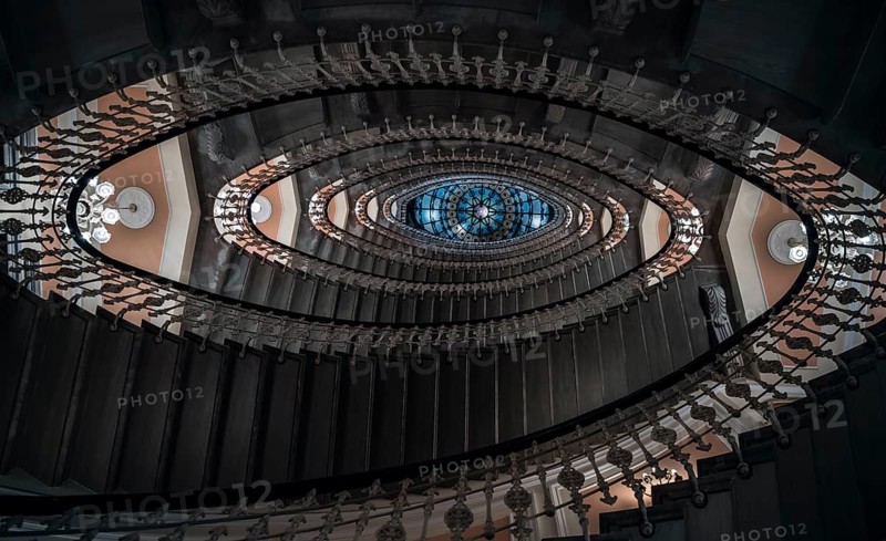 Eye-catching image with staircase design in a spiral form, a pattern of oval figures, illuminated by chandeliers, viewed from under, in Genoa, Italy, Europe