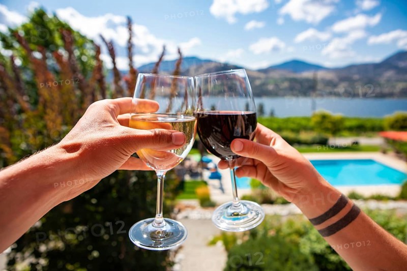 Okanagan Valley wine tasting tour, wineries visit during summer and spring vacations concept, man and woman hands toasting red and white wine glasses