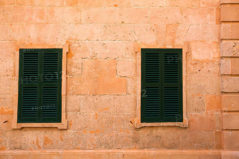 Ciutadella Menorca wooden shutter window on grunge yellow downtown wall at Balearic islands